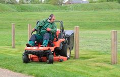 a man riding on the back of a red lawn mower