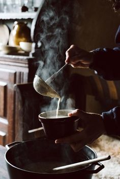 a person stirring something in a pot on a stove top with steam rising from it