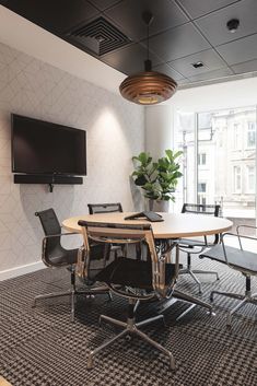 an office meeting room with a large table and chairs in front of a flat screen tv