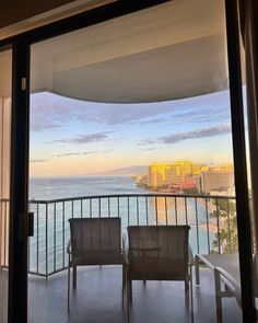 two chairs sitting on top of a balcony next to the ocean