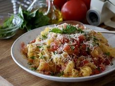 a white plate topped with pasta covered in sauce and parmesan cheese