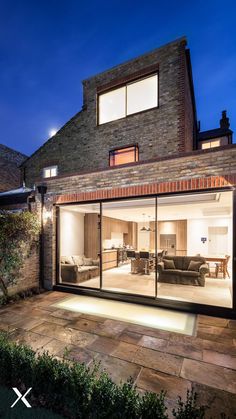 an open living room and dining area are lit up at night in front of a brick building