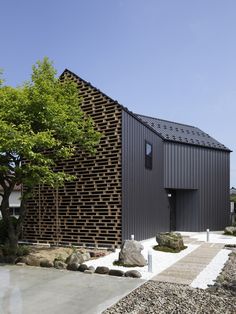 a building made out of wooden slats on the side of a road with trees and rocks around it