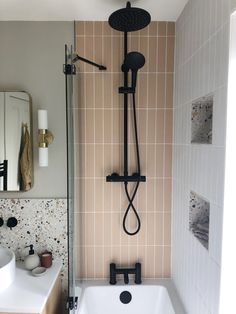 a bathroom with a sink, shower head and tiled walls in it's corner