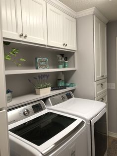 a white washer and dryer in a room with cabinets on either side of the washer and dryer