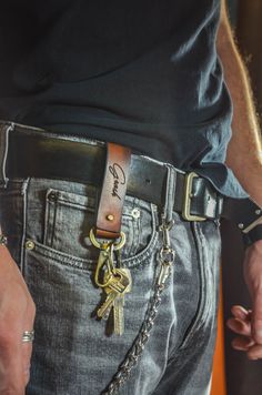 a man wearing a belt with a gold key on it's side and a chain attached to his waist