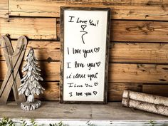 a wooden sign sitting on top of a mantle next to a christmas tree and other decorations