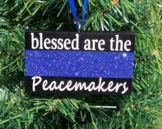 a blue ornament hanging from a christmas tree with the words, blessed are the peacemakers