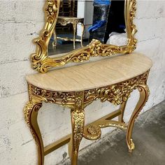 an ornate gold painted console table with mirror