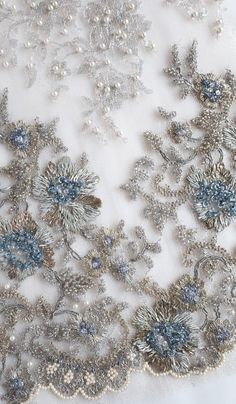 Couture French Lace | Silver Metallic Lace embroidered with a vintage feel and tiny accents of blue Elegant Silver Floral Embroidered Fabric, Elegant Silver Embellished Embroidered Fabric, Elegant Embellished Multicolor Embroidered Fabric, Silver Embellished Embroidered Fabric For Reception, Elegant Embroidered Multicolor Fabric, Elegant Blue Embroidered Fabric With Floral Details, Elegant Blue Floral Embroidered Fabric, Elegant Multicolor Embroidered Fabric For Reception, Elegant Blue Embellished Embroidered Fabric