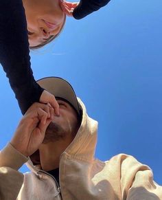 a man and woman are looking up into the blue sky with their hands on each other's shoulders