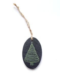 a wooden ornament with a green christmas tree on it's side hanging from a string