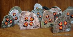 four painted rocks sitting on top of a wooden table next to each other with ladybugs on them