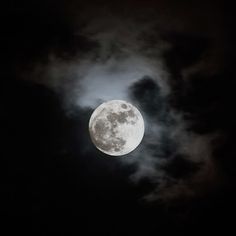 the full moon is seen through dark clouds