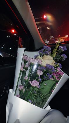 flowers are wrapped in white paper on the back seat of a car at night time