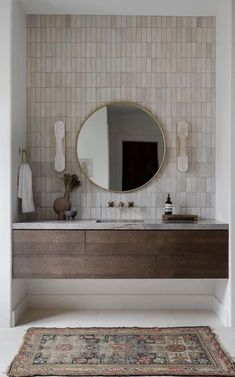 a bathroom with a rug, sink and mirror