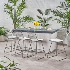 an outdoor bar with four stools and potted plants