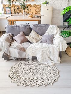 a living room with a couch, rug and potted plants on the floor in front of it