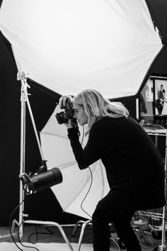 a black and white photo of a woman with a camera in front of an umbrella