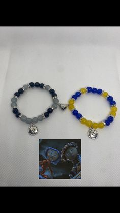 two bracelets with charms on them sitting next to each other