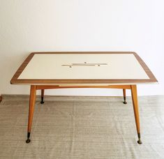 a coffee table with an interesting design on the top and bottom, sitting against a white wall