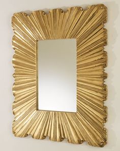 a gold framed mirror hanging on the wall next to a white wall in a room