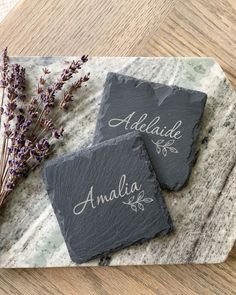 two slate coasters with names on them and lavender sprigs in the background