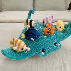 a crocheted fish pillow on top of a bed with pillows in the background