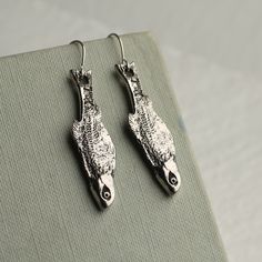 These beautifully detailed and novel earrings feature a stylised silver sardine, hung from a simple silver plated earwire.   Measuring 35mm (just less than 1.5 inches) in length, the fish charm is designed to hang just below the earlobe.  These charms are great quality, but are light and comfortable to wear.   This piece of handmade jewellery comes packaged in a nice recycled gift box with a handmade tag, all ready to give or keep. 🖤 FASTER SHIPPING 🖤 Need this fast? We offer a Faster Shipping option here: https://www.etsy.com/uk/listing/100107311/faster-shipping-priority-post-upgrade 🖤 GIFT MESSAGE & WRAP SERVICE! 🖤 https://www.etsy.com/uk/listing/750160511/gift-wrap-wrapping-personalised-card?ref=listings_manager_table Silver Fish-shaped Earrings With Fish Hooks, Silver Fish-shaped Earrings With Ear Wire, Nickel-free Silver Fish-shaped Earrings, Sardine Fish, Fish Earrings, Silk Purse, Drop Earrings Silver, Handmade Tags, Photo Locket