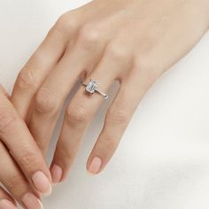 a woman's hand with a diamond ring on her left hand and the other hand holding an engagement ring