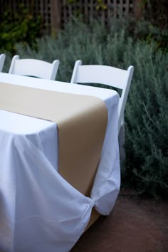 the table is covered with white cloths and has a name tag attached to it