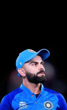 a man with a beard wearing a blue shirt and cap looking off to the side