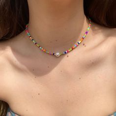 Multicolored beaded choker, the perfect accessory for anyone who loves to add a pop of color to their outfit! Handcrafted with love , this choker features a delicate beaded design that showcases a beautiful array of hues. Shades of pink, purple, blue, green, orange, red, and yellow that blend seamlessly together. A single pearl accent in the center adds a touch of elegance and sophistication to the overall design. This choker is also incredibly comfortable to wear, with a soft and lightweight construction that won't weigh you down. Whether you're dressing up for a special occasion or adding a colorful touch to your everyday look, this beaded choker is sure to turn heads and make a statement. The perfect addition to any jewelry collection, this choker is a must-have for anyone who loves bol Festival Letter Beads, Multicolor Tiny Beads Choker For The Beach, Colorful Beaded Necklaces With Letter Beads, Beaded Letter Beads Choker Necklace, Festival Letter Beads Choker Necklace, Colorful Letter Beads Necklace, Multicolor Round Beads Choker For Summer, Multicolor Beaded Chain Choker, Multicolor Beaded Choker For Summer