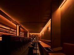 a dimly lit bar with stools and bottles on the wall