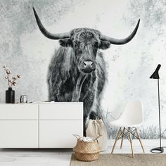 a black and white photo of a long horn bull standing in front of a wall mural