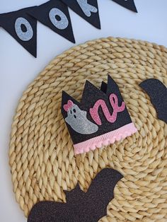 there is a black and pink crown on top of a wicker basket with bats