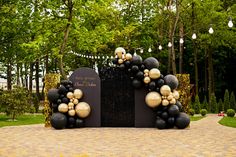 black and gold balloons decorate the entrance to a garden