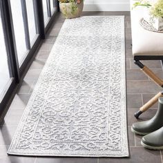 a white rug with an ornate design on the floor next to a pair of rubber boots