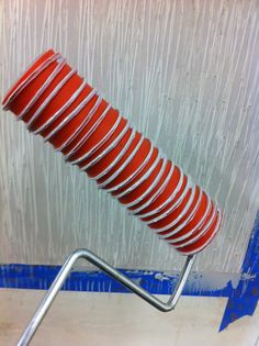 a red and white striped object on a metal stand in front of a gray wall