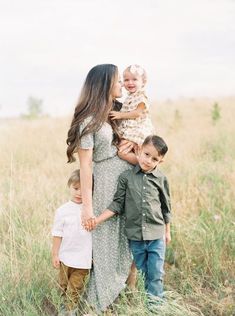 a mother and her two sons are standing in the tall grass with their arms around each other