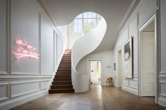 a staircase in an elegant home with white walls and wood flooring is illuminated by pink neon lights