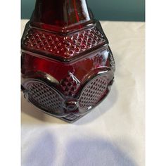 a red vase sitting on top of a white table