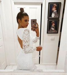 a woman taking a selfie in front of a mirror wearing a white wedding dress