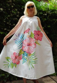 a woman wearing a white dress with flowers painted on it