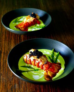 two black plates with food on them sitting on a wooden table next to each other