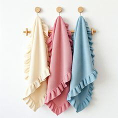 three towels hanging on the wall next to each other with wooden pegs in front of them