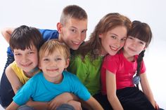 a group of young children sitting next to each other on a white surface with one boy smiling at the camera