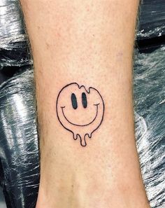 a smiley face tattoo on the ankle