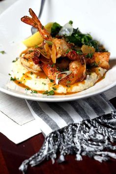 a white plate topped with shrimp and grits