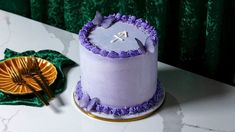 a purple cake sitting on top of a table next to a plate and fork,